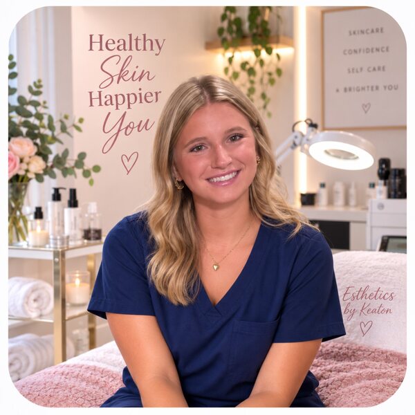 Keaton smiling in navy scrubs in a softly styled esthetics room.